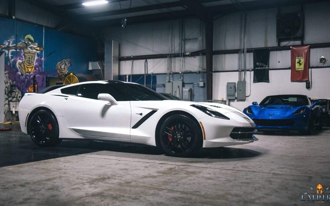 Image of a white sports car parked in the Empire Auto Spa Garage. The car has a ceramic coating applied to it. The coating is clear and transparent, and it gives the car a shiny and glossy finish.