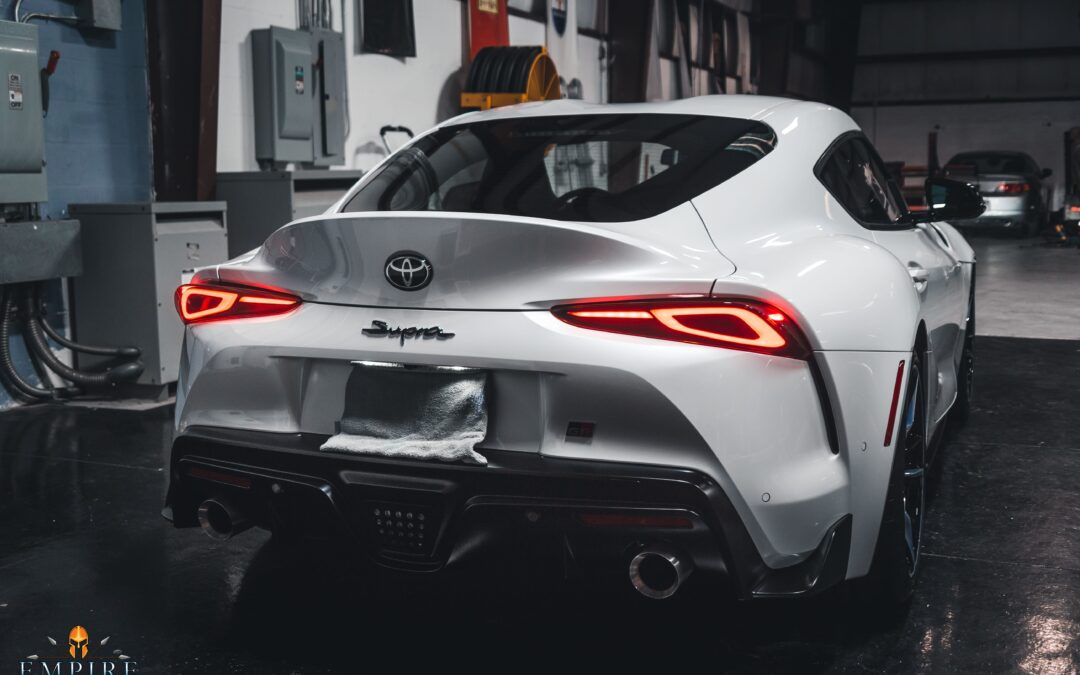 A white Toyota Supra parked in a garage. The image contains the text "EMPIRE".