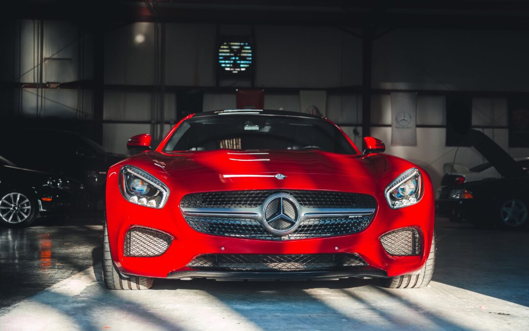 Image of a professional auto detailer using a microfiber cloth to clean the interior of a car. The car is a red Mercedes-AMG GT S. The image is captioned with the text "Auto Detailing 101: What You Need to Know - A Comprehensive Guide by Empire Auto Spa".
