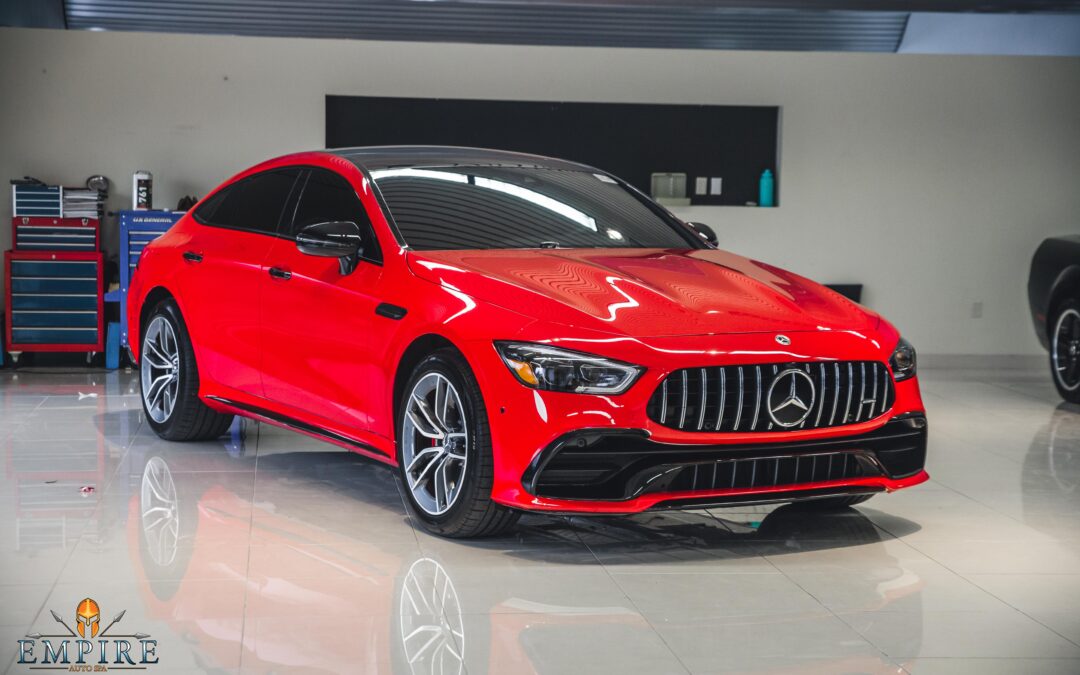 Red Mercedes-Benz AMG GT53 coupe parked in a garage. The text "EMPIRE" is visible on the garage door.