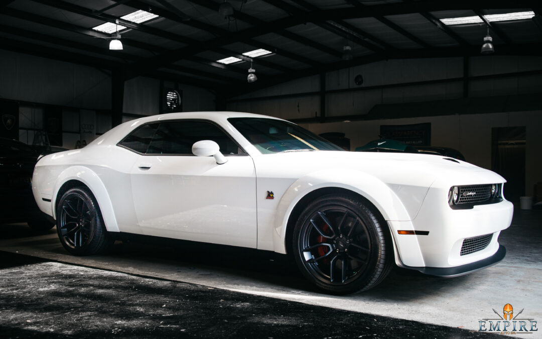 A white muscle car sitting in a garage. The car has the text "EMPIRE" on it. The image is from the blog post "How Mobile Detailing Works: A Step-by-Step Guide - Insights from Empire Auto Spa".